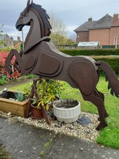 Life size wooden model of a horse jumping for outside show. Finished in brown.