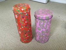 Two tall round floral decorated biscuit tins