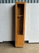 An Ercol narrow elm and glazed cabinet