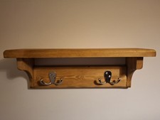 Rustic wooden wall-mounted coat rack with a shelf and double hooks
