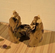 2 Mud Men Sitting On Bench