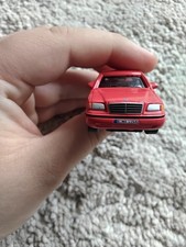 red die-cast model of a Mercedes-Benz C-Class (W202).