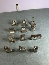 Set of twelve silver colour miniature quartz clocks. Sold as non working. VGC