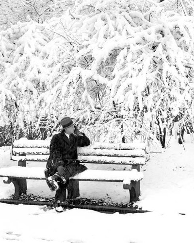 Man sits park bench and - on, can