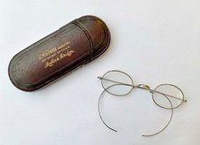 A pair of antique wire-rimmed spectacles with a leather case. 