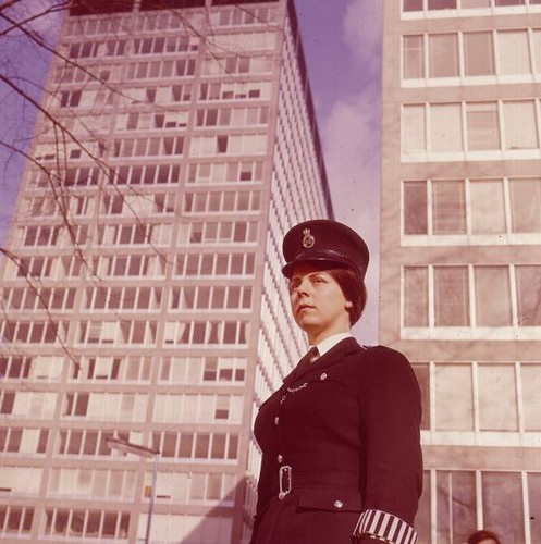 Policewoman stands front of - in,