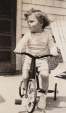 Child Riding Tricycle on Porch