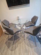 Round Glass dining table with four grey chairs