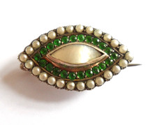 Antique silver brooch inset with split pearls, green stones and mother of pearl.