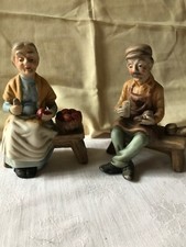 Old Man And Lady Sat On Benches Making Shoes And Basket Fruit 