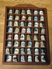 COLLECTION OF 48 THIMBLES IN A WOODEN DISPLAY CASE.