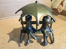 old brass frogs on bench with umbrella