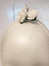 White flower girl headdress wrapped with satin ribbon and small floral design.