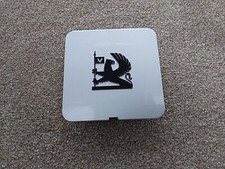 VAUXHALL SQUARE PLASTIC  BADGE FEATURES VAUXHALL GRIFFIN ON A SILVER BACKGROUND.