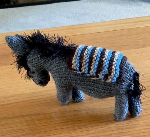 Hand knitted grey donkey with - hand,