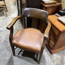 This is an antique oak captain's chair with a Tan leather seat Heavy And Sturdy
