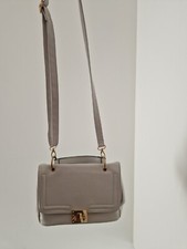 Grey shoulder bag with gold buckle and handle.