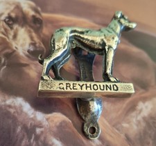 A small brass vintage door knocker featuring a three dimensional greyhound.