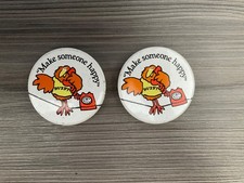 2 x BUZBY "Make someone happy" badges.
