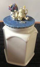 White Hexagonal Cookie Jar; Various Items on Lid (Teapot, Flowers, Candle, Cake)