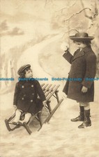 R642597 Winter. The child is sitting on a sled. A child with a snowball in his h