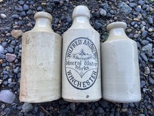 Trio of antique white stoneware bottles, one printed from Wilfred Andrews' St. S