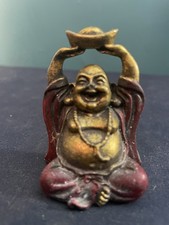 A vintage decorative bronze-colored Laughing Buddha figurine with a gold ingot.