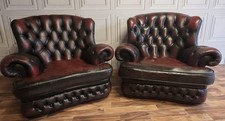 A pair of ox blood red leather chesterfield  wing back chairs 