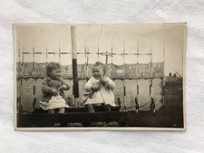 Two young children sitting in a coconut shy at a fair vintage unbranded postcard