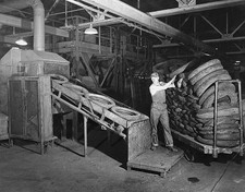 Workmen are shown feeding scrap tires into grinding machine which- 1941 Photo