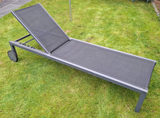 Grey metal frame reclining sunlounger with wheels, textile fabric covering