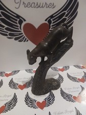 carved wooden sculpture of a big cat, perched on a branch