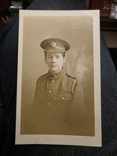 WW1 REAL PHOTO POSTCARD. YOUNG BRITISH SOLDIER IN UNIFORM, CAP BADGE