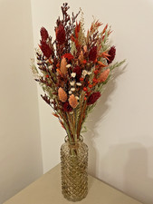 Dried flowers bouquet in Natural, oranges & rich red in a light brown glass vase