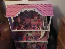 pink and purple doll house with furniture and lots of extra dolls & accessories