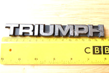 TRIUMPH SILVER ON BLACK CAPITAL LETTERS 15.3cm. CAR BADGE