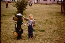 BOY POSING NEXT TO PEDDLE CAR