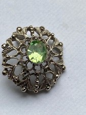 A vintage silver coloured brooch set with a peridot green type stone