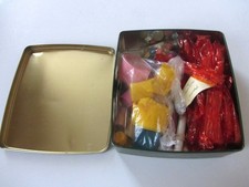 Vintage craft items, crepe paper, streamers, glitter and beads in pretty tin