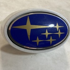 USED Subaru white with blue and gold front has screw on back deep badge