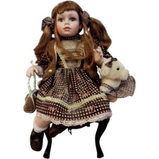 Porcelain Katy Doll With Floral Dress & Teddy Bear Accessory sitting on a chair