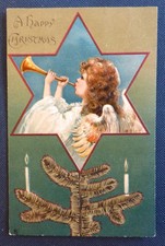 Tuck 8264 Christmas: Angel playing trumpet in a star inset on tree. Embossed.