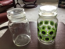A pair of empty Douwe Egberg coffee/storage jars - one clear one apple patterned