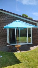 Pale blue and wood rectangular patio sunshade, parasol with stone base.