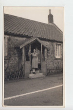 RPPC Lady standing at entrance porch of cottage. Unknown location.