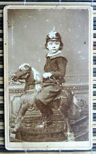 A little boy in on a ride on toy horse. Pimpled hat & toy sabre. CDV