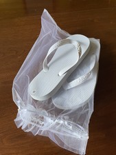 36 unworn wedding flip flops in organza bags and presentation wicker basket.