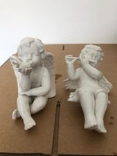 A pair of porcelain Cherub Angels.One with a dove and one with a flute.