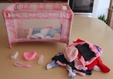 Doll in a cot with clothes and accessories