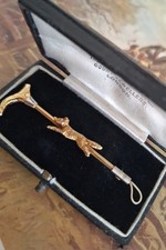 A quality stockpin, English hunting attire. A gold running fox atop a hunt whip.